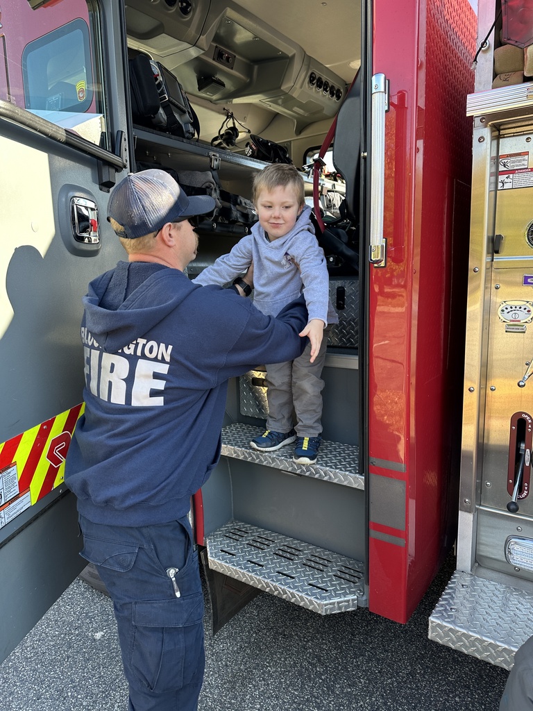 firefighter helping a preK student out of a fire truck