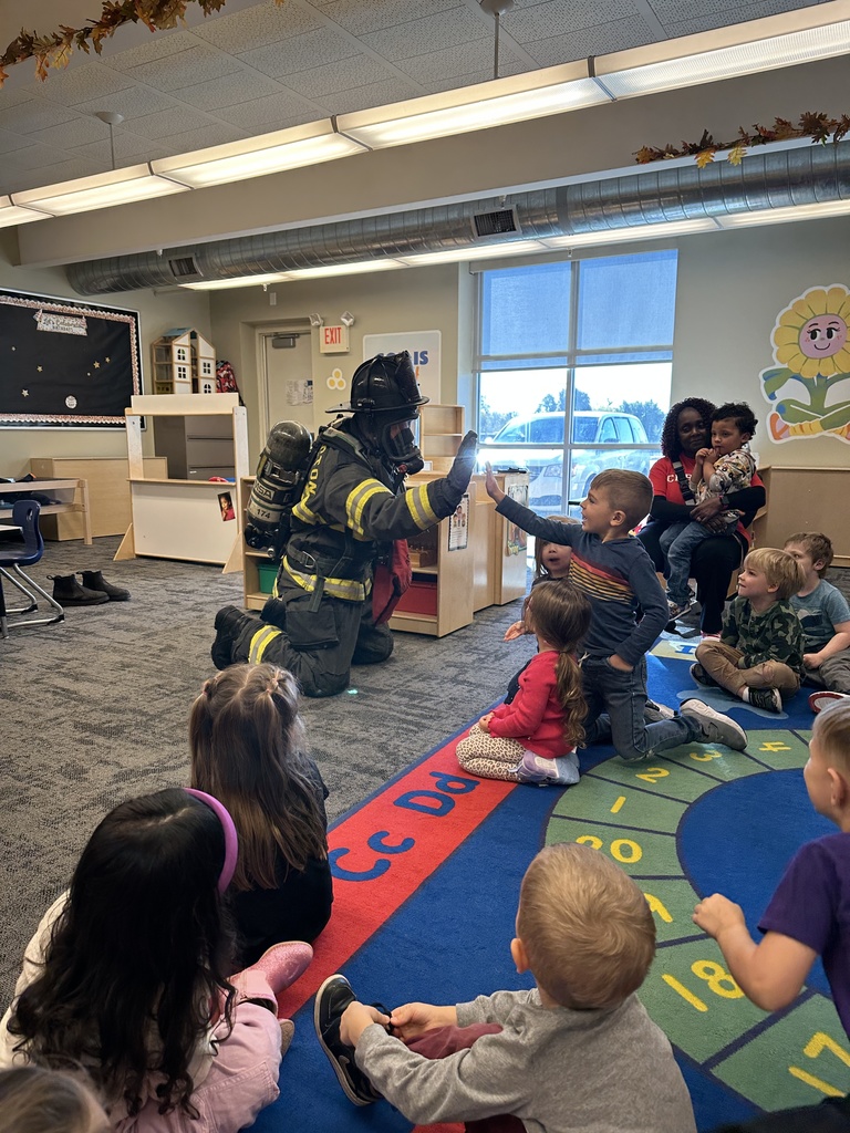 firefighter on his knees giving a young student a high five