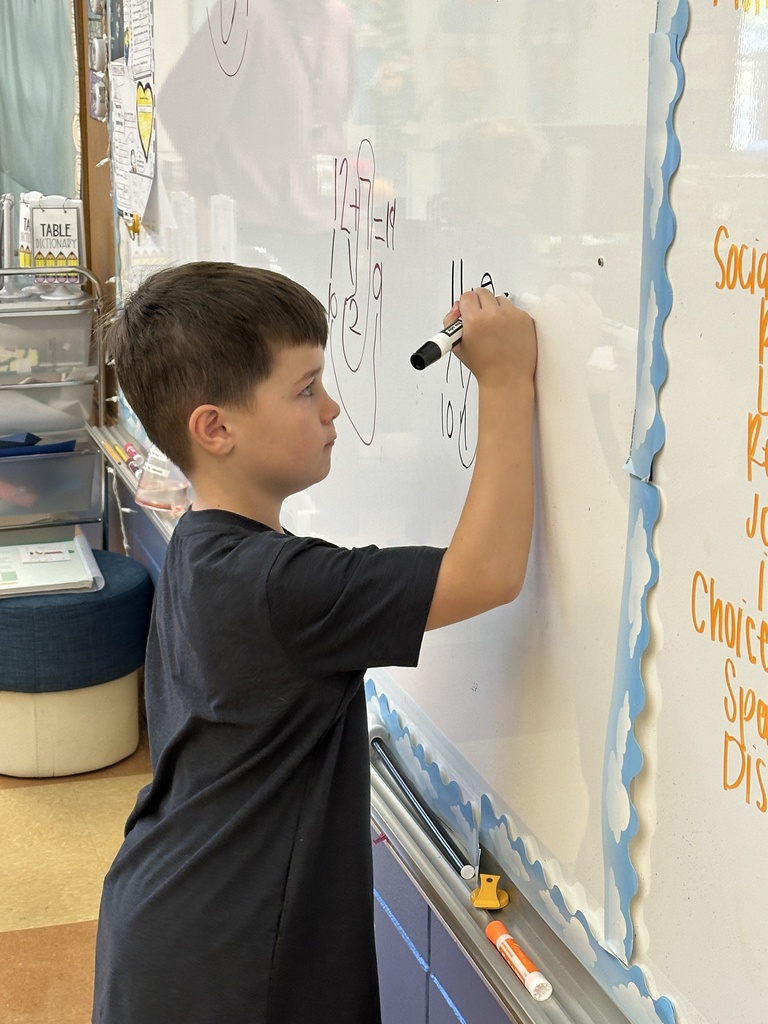 first grade student student writing on the white board