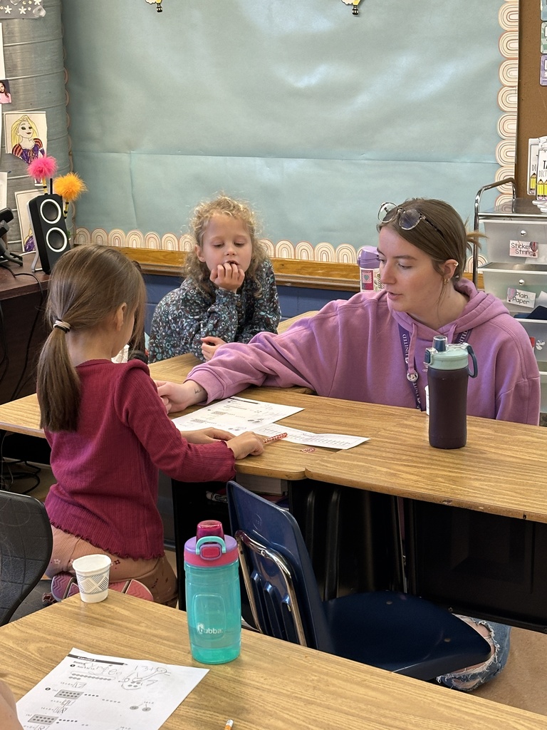 first grade teacher helping a student at her desk