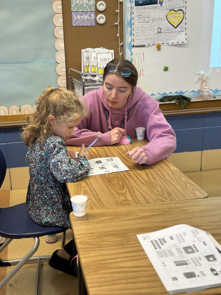 first grade teacher helping a student at her desk