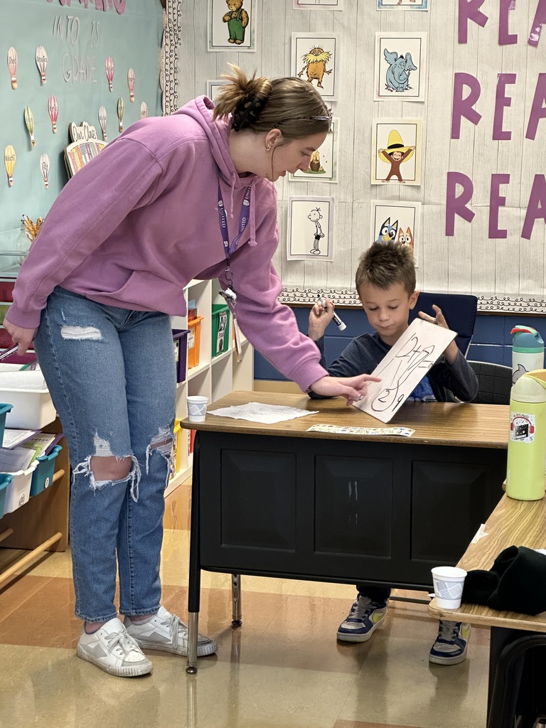 first grade teacher helping a student at his desk