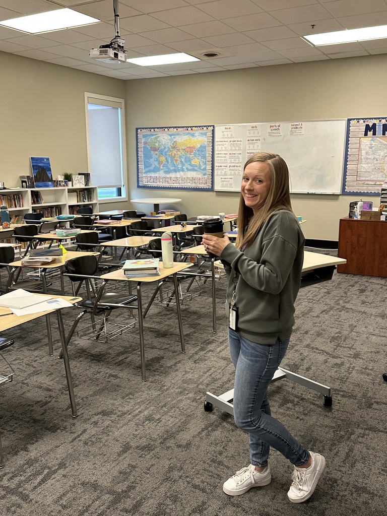 teacher smiling and holding a cup of coffee