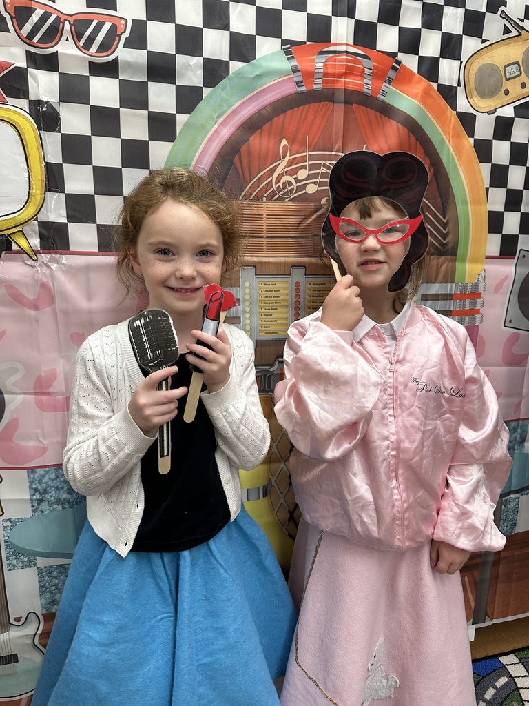 two girls dressed in 50's clothes at a photo booth