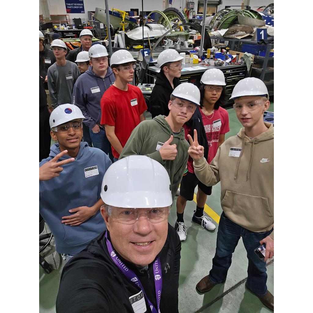 selfie of a chaperone with a group of students in an aircraft maintenance hangar