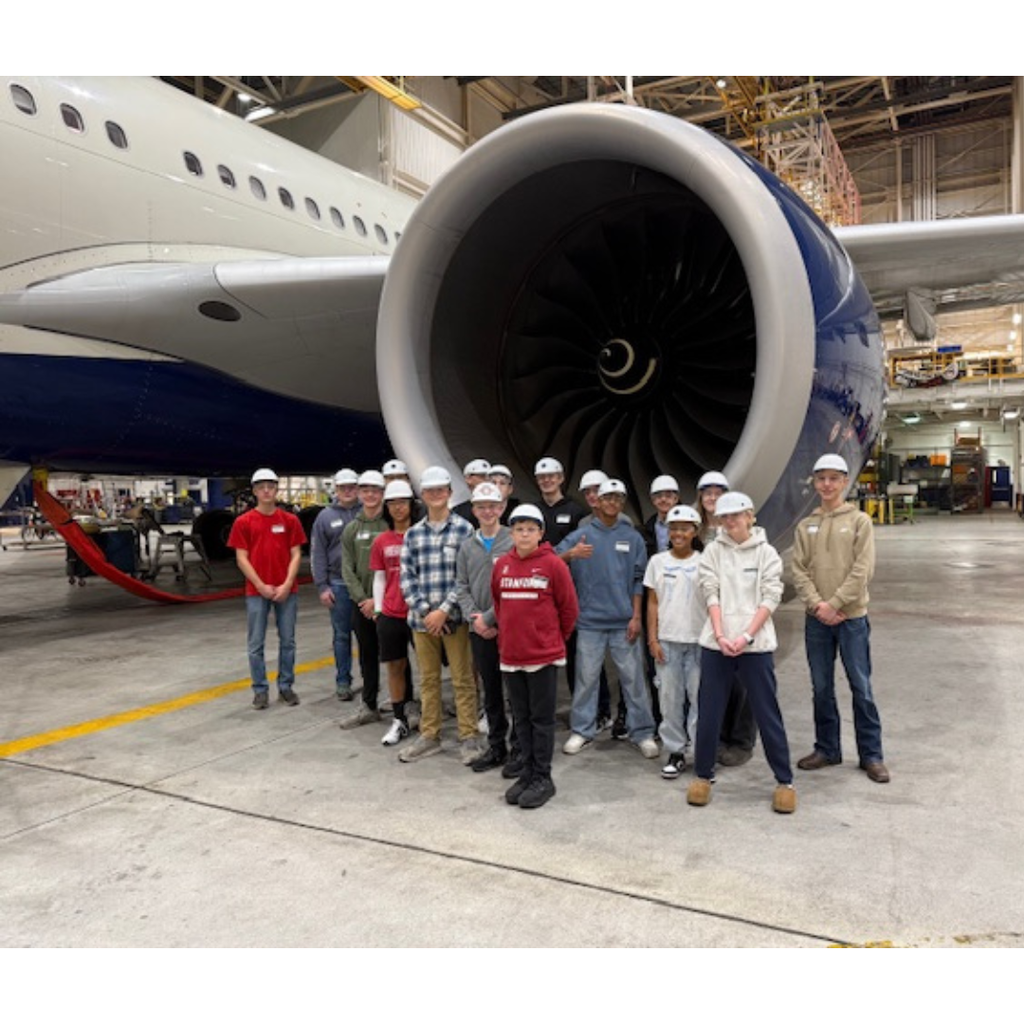 group photo of students standing under the engine of an Airbus 330