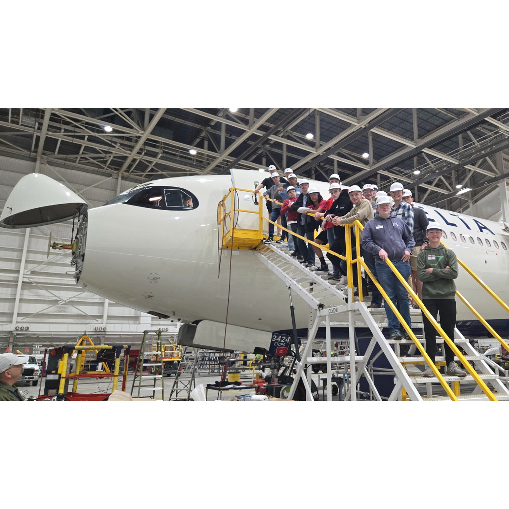 group photo of students standing on a staircase leading up to an Airbus 330