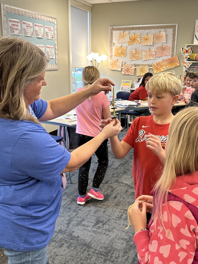 teacher and student holding a pencil with two magnets on it repelling each other