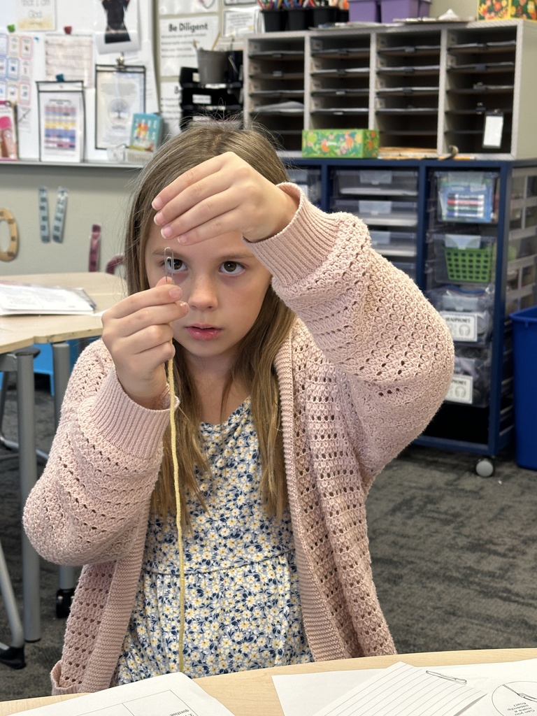girl trying to get a paper clip to 'float' using a magnet