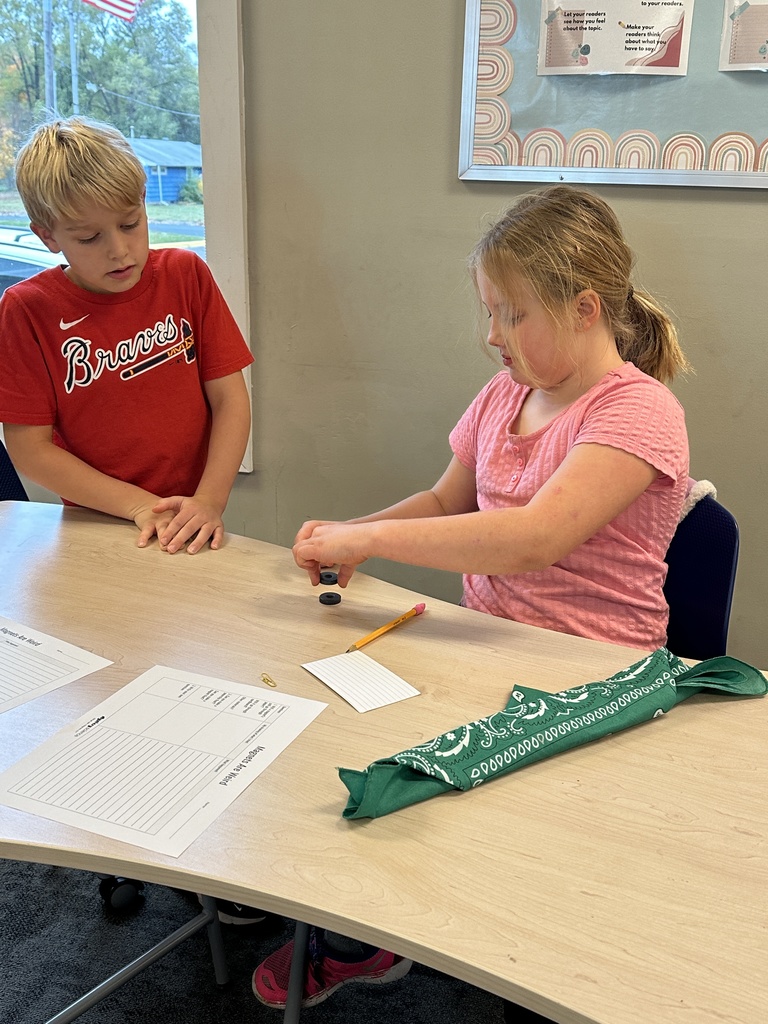 girl holding two magnets and watching them repel as boy watches