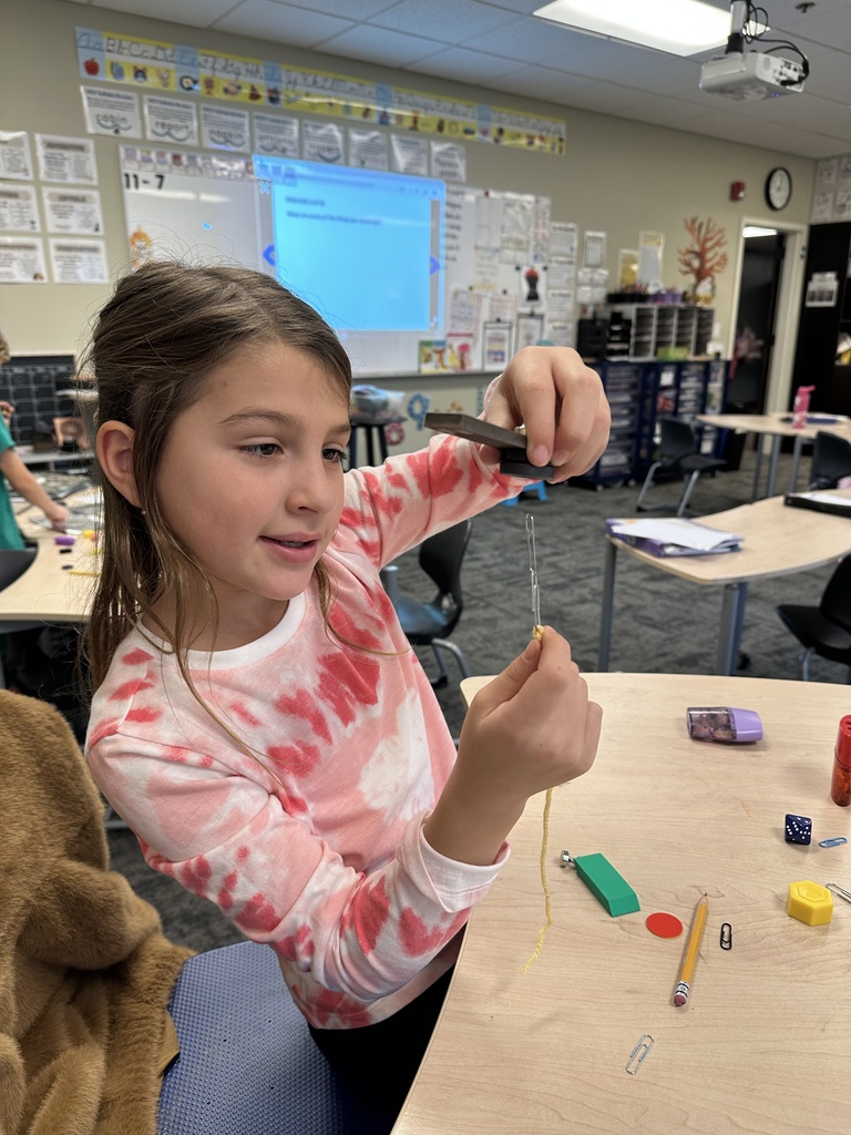 girl trying to get a paper clip to 'float' using a magnet