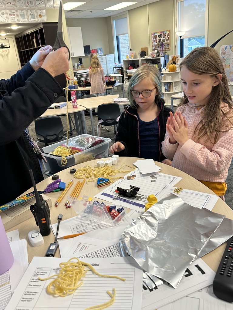 students looking at a table full of different objects for them to choose to experiment with using magnets