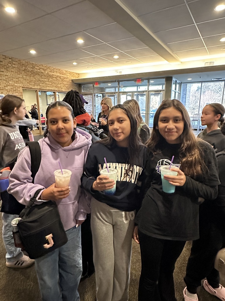 two students holding their drinks from the coffee cart