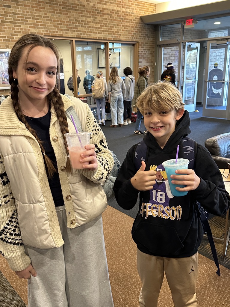 two students holding their drinks from the coffee cart