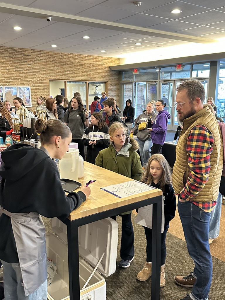 student taking a coffee order from a parent and two kids
