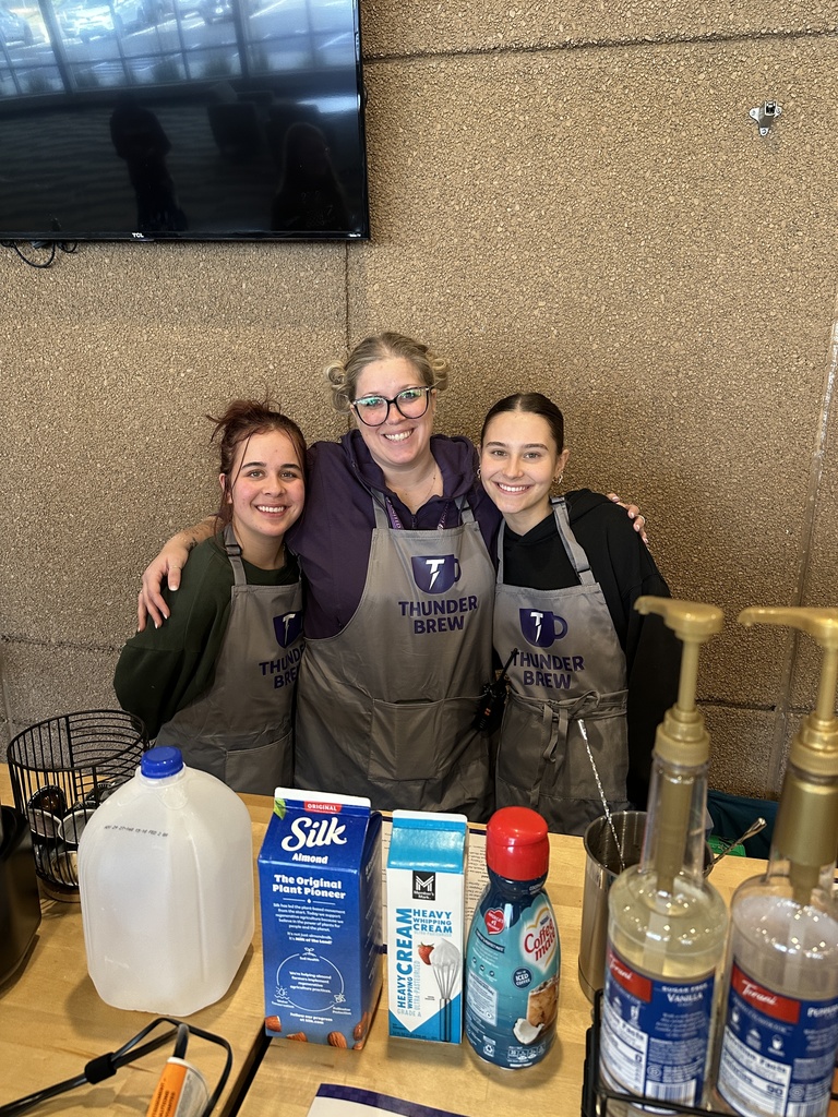three young women with aprons on working as baristas