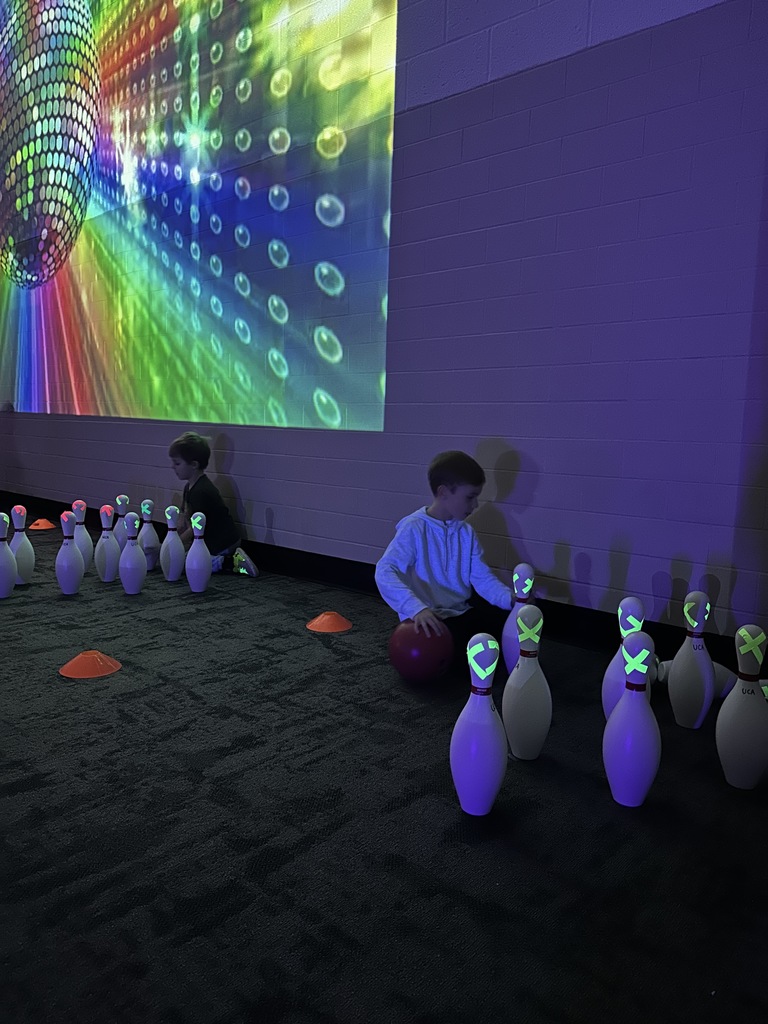 elementary students setting up bowling pins after they knocked them down