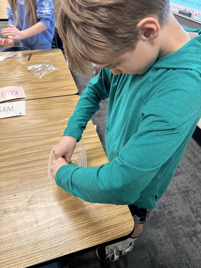 student pressing clay into a container