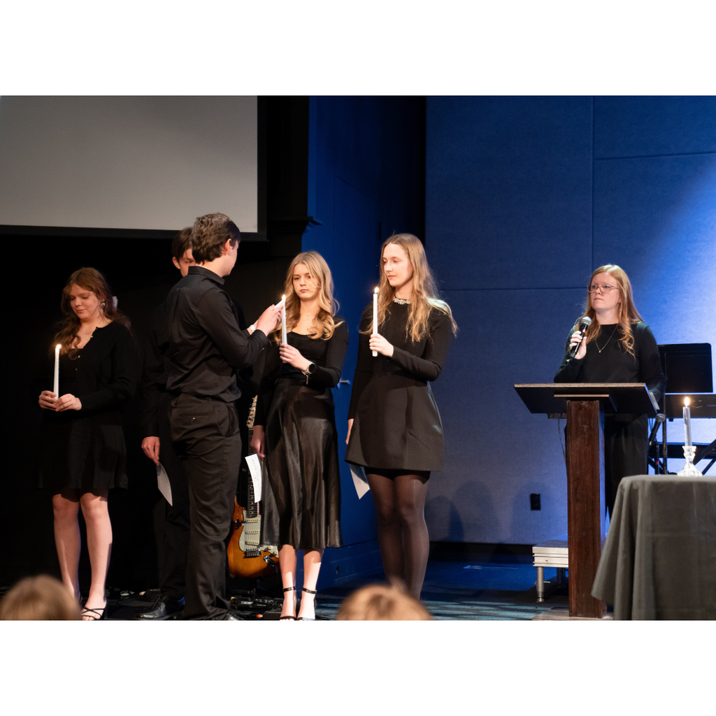 student lighting their candle from one of the officer's candles