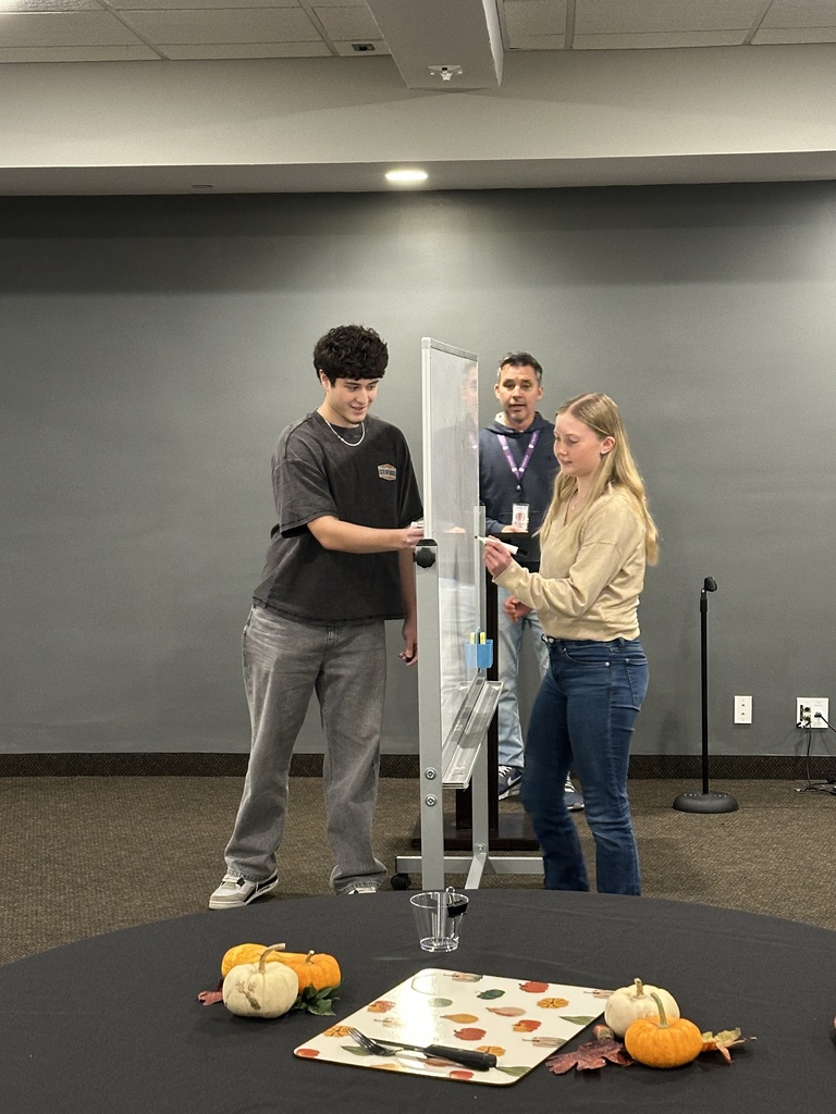students drawing on a white board as they play Pictionary