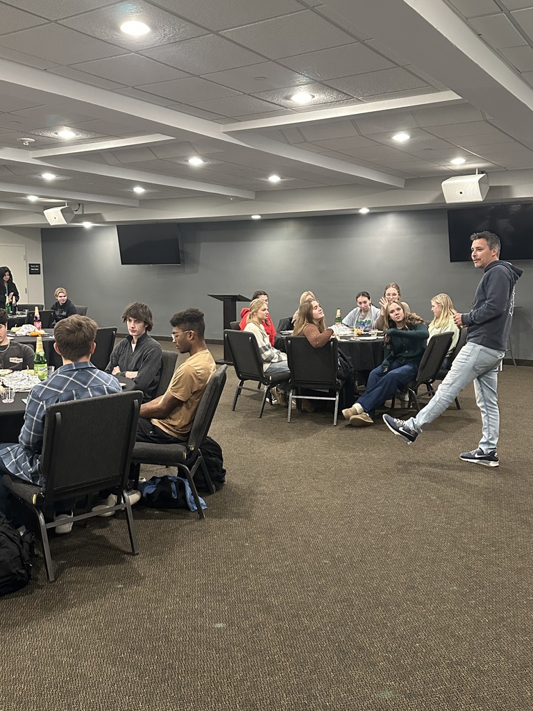head of school speaking to tables of 12th graders