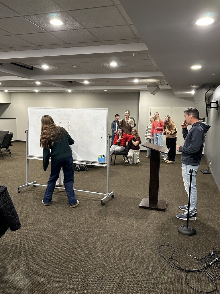 students drawing on a white board as they play Pictionary