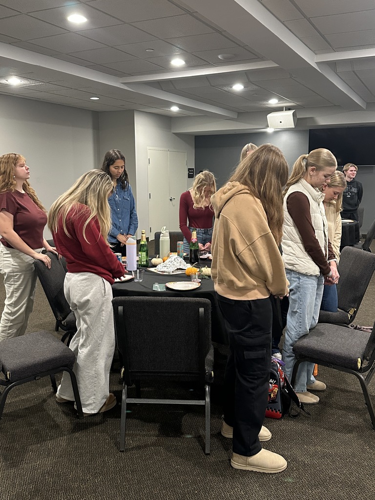 group of students standing and praying before they eat together