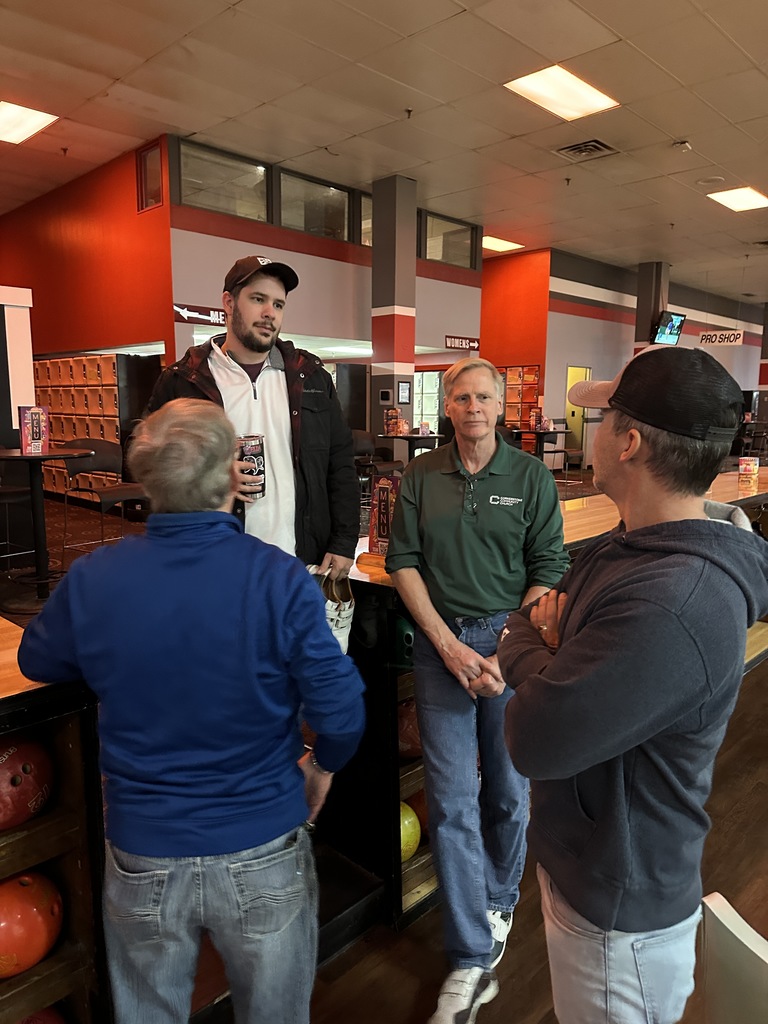 group of teachers standing and talking at a bowling alley