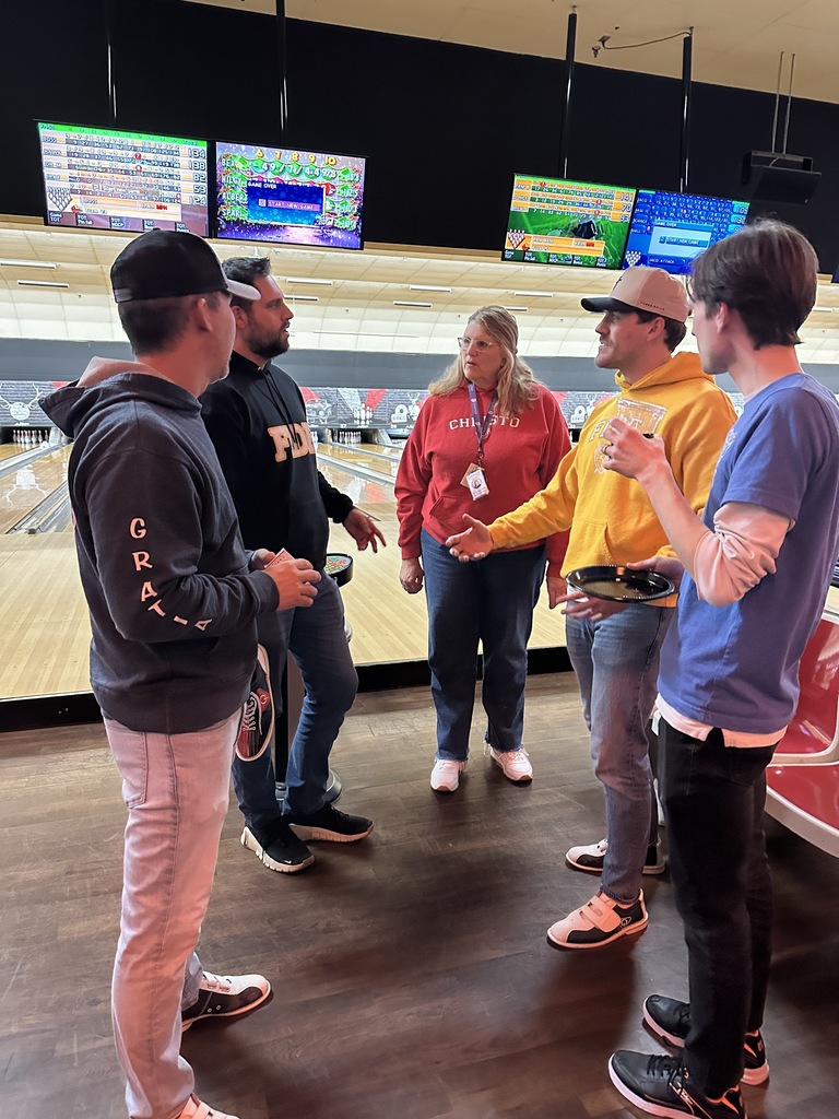 group of teachers standing and talking at a bowling alley