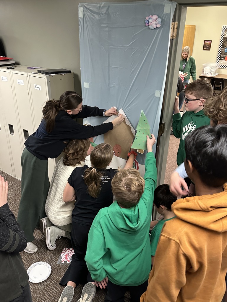 middle school students decorating a classroom door with a Christmas theme
