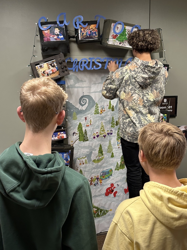 high school students decorating a classroom door with a Christmas theme
