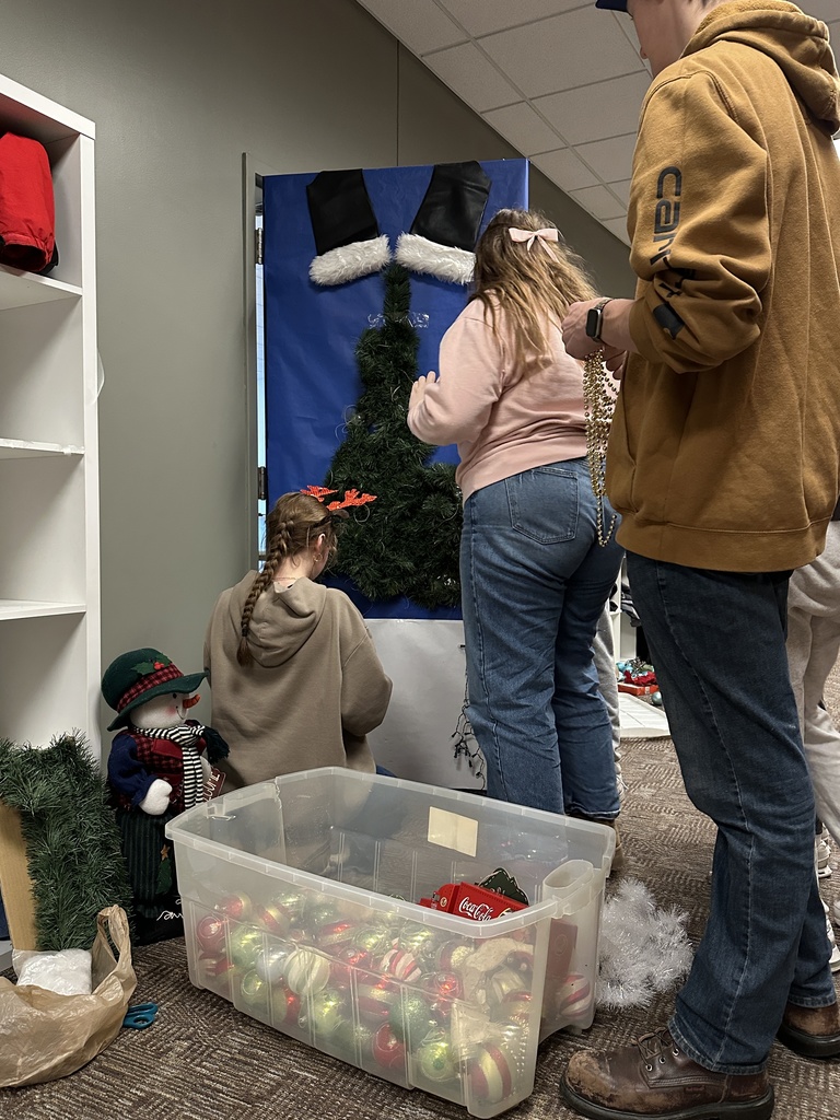 high school students decorating a classroom door with a Christmas theme