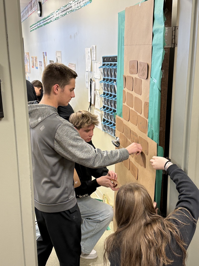 high school students decorating a classroom door with a Christmas theme
