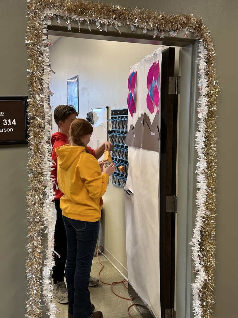 high school students decorating a classroom door with a Christmas theme