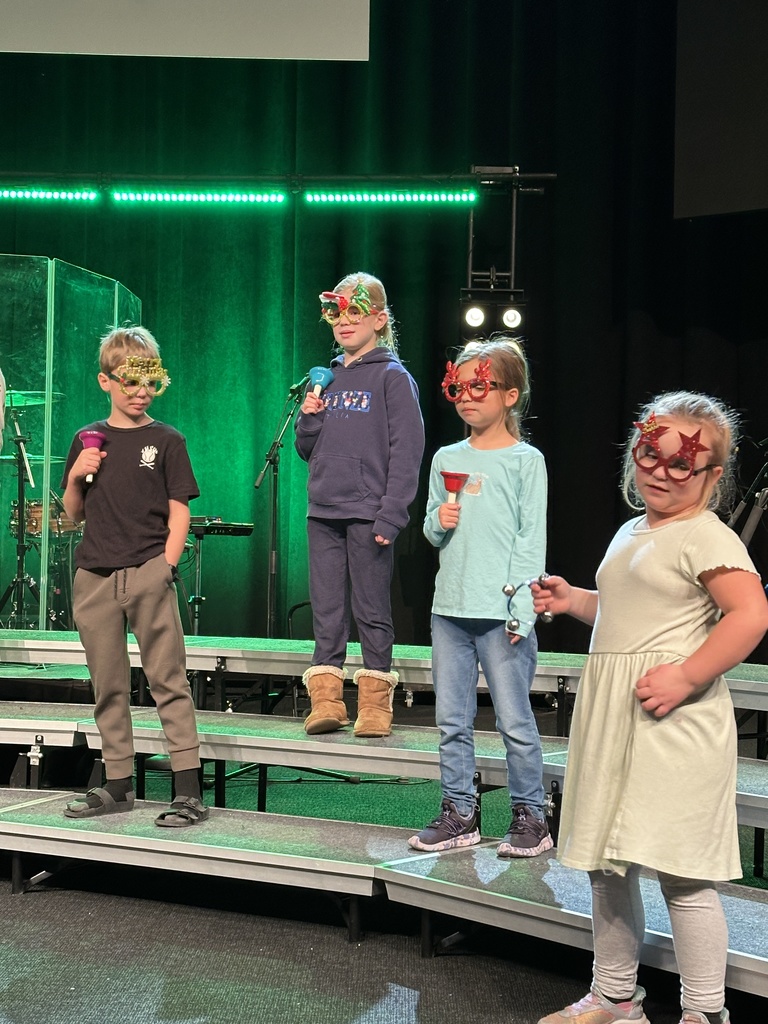 students singing on stage, some holding props