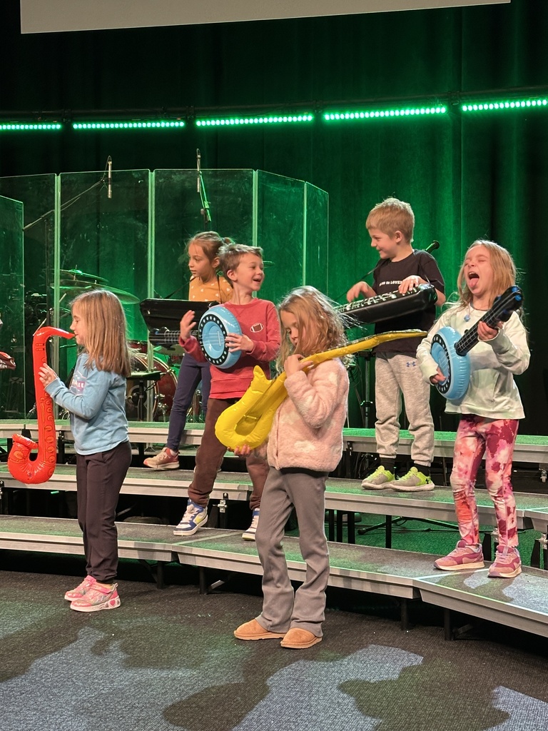 students holding inflatable students while singing on stage