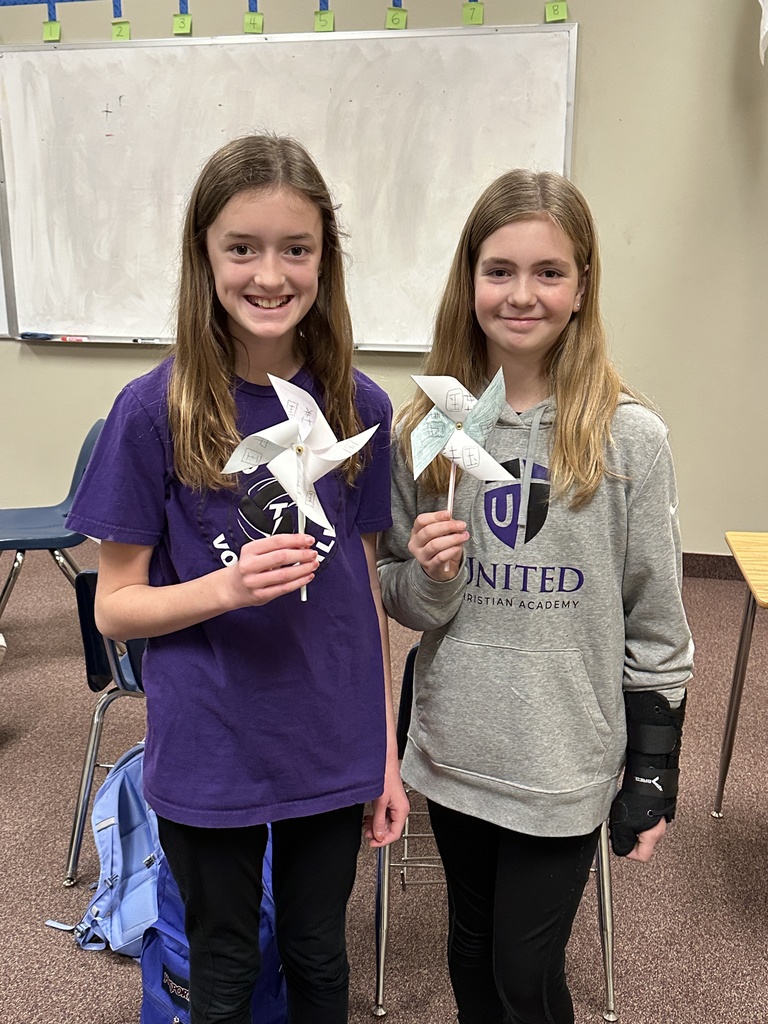 two students showing the windmills they made with Chinese characters written on them