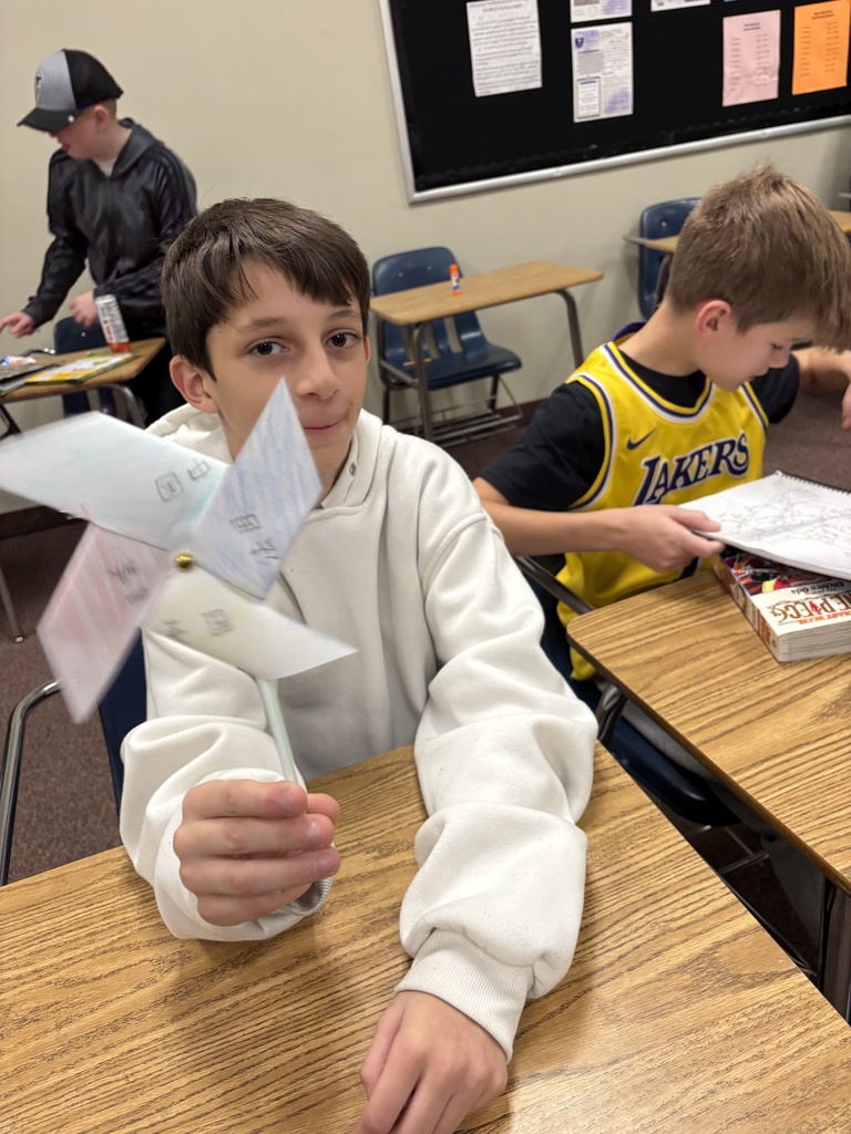 one student showing the windmills they made with Chinese characters written on them