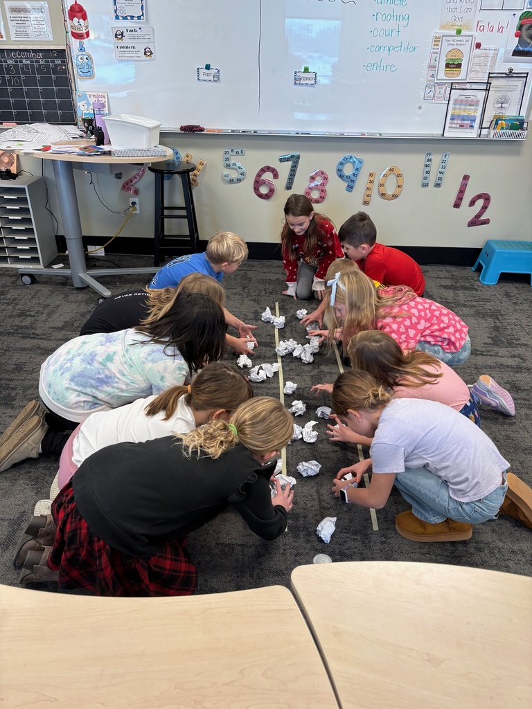 students lined up in the middle of a classroom ready to pick up paper snowballs and start a "snowball fight"