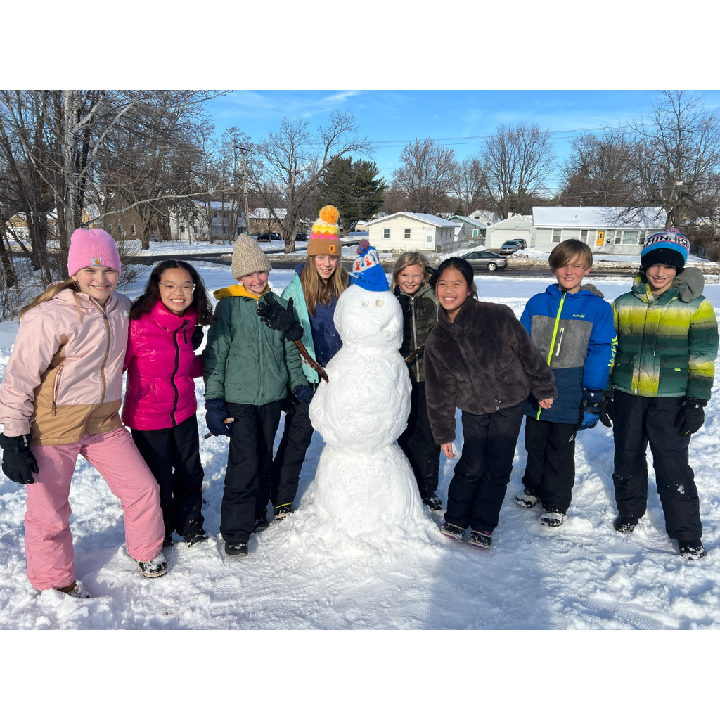 group of elementary students making a snowman at recess