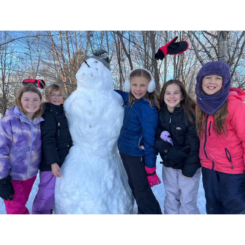 group of elementary students making a snowman at recess