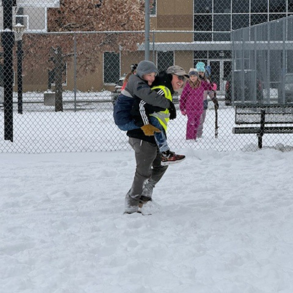 principal playing in the snow with students