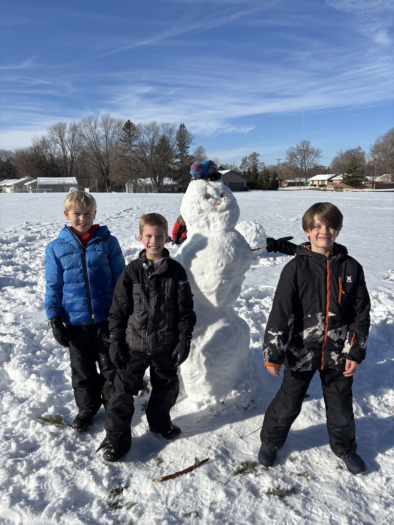 three elementary boys standing next to a snowman