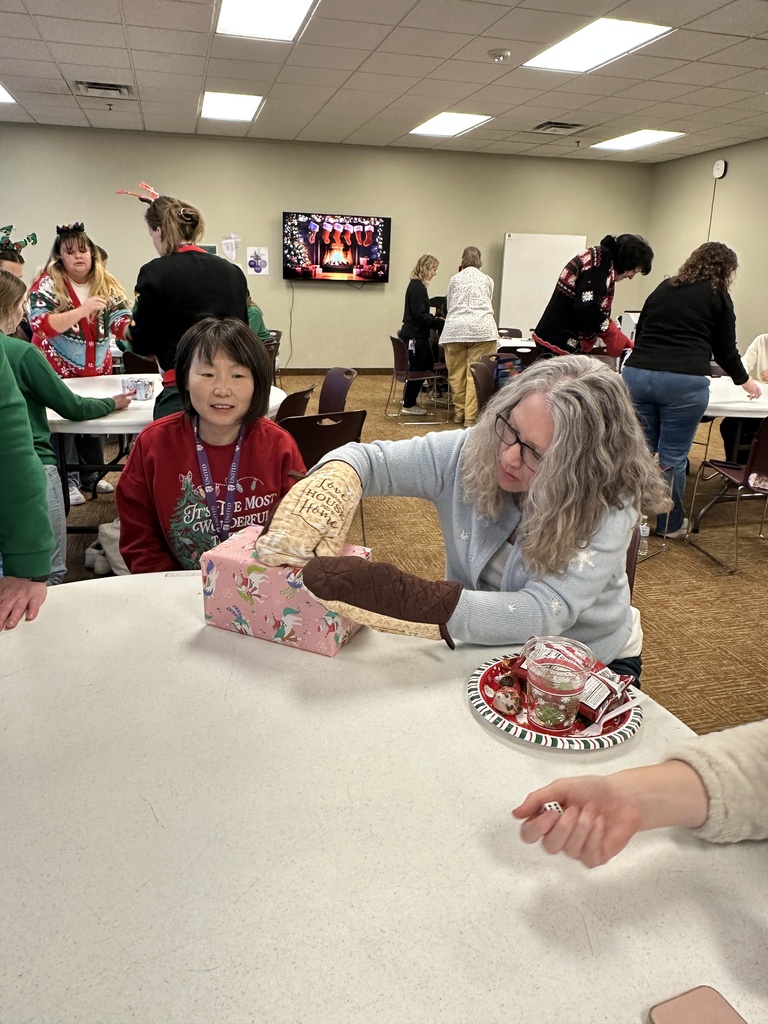staff member trying to unwrap a gift with oven mits on