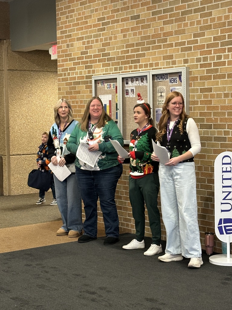 staff members singing christmas carols and playing instruments as students walk into the building