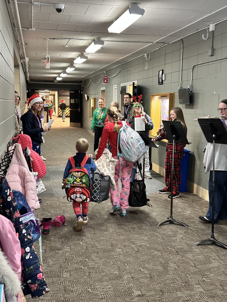staff members singing christmas carols and playing instruments as students walk into the building