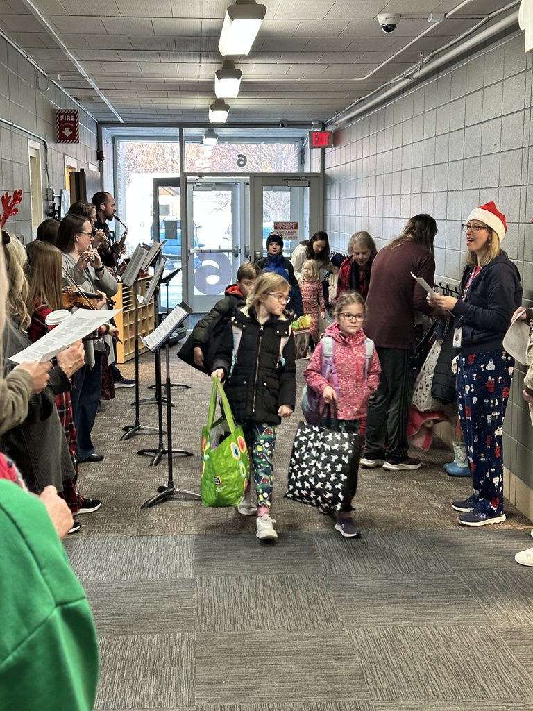 staff members singing christmas carols and playing instruments as students walk into the building