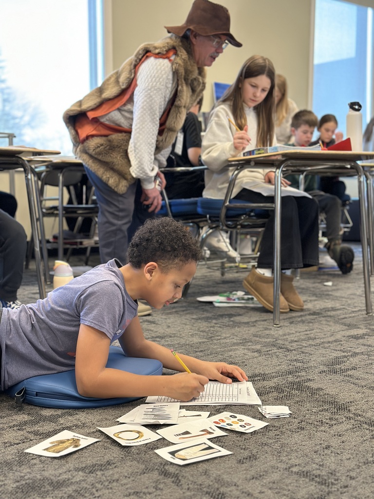 student sitting on the floor counting his beaver pelts and other goods