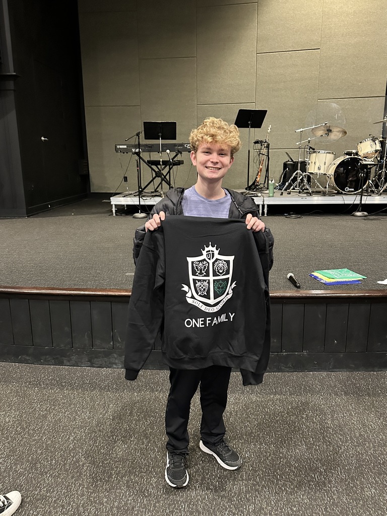 student of the quarter winner holding up the sweatshirt that he won