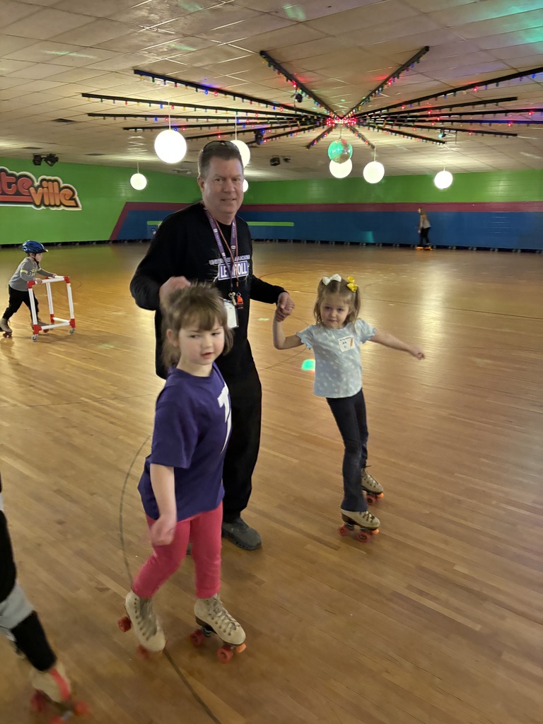 teacher helping young girls roller skate
